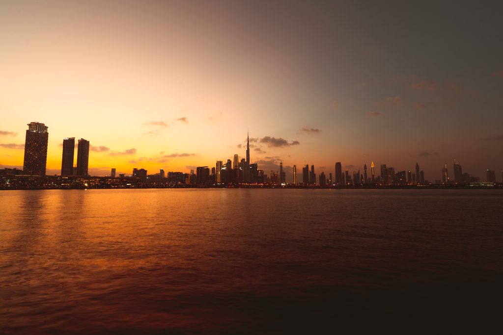 Aerial view of the Dubai skyline at sunset showing the Burj Khalifa and DIFC business district
